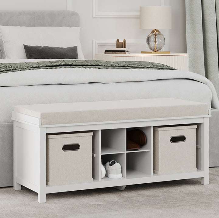 white shoe storage bench with cubbies and bins placed at the end of a bed in a master bedroom